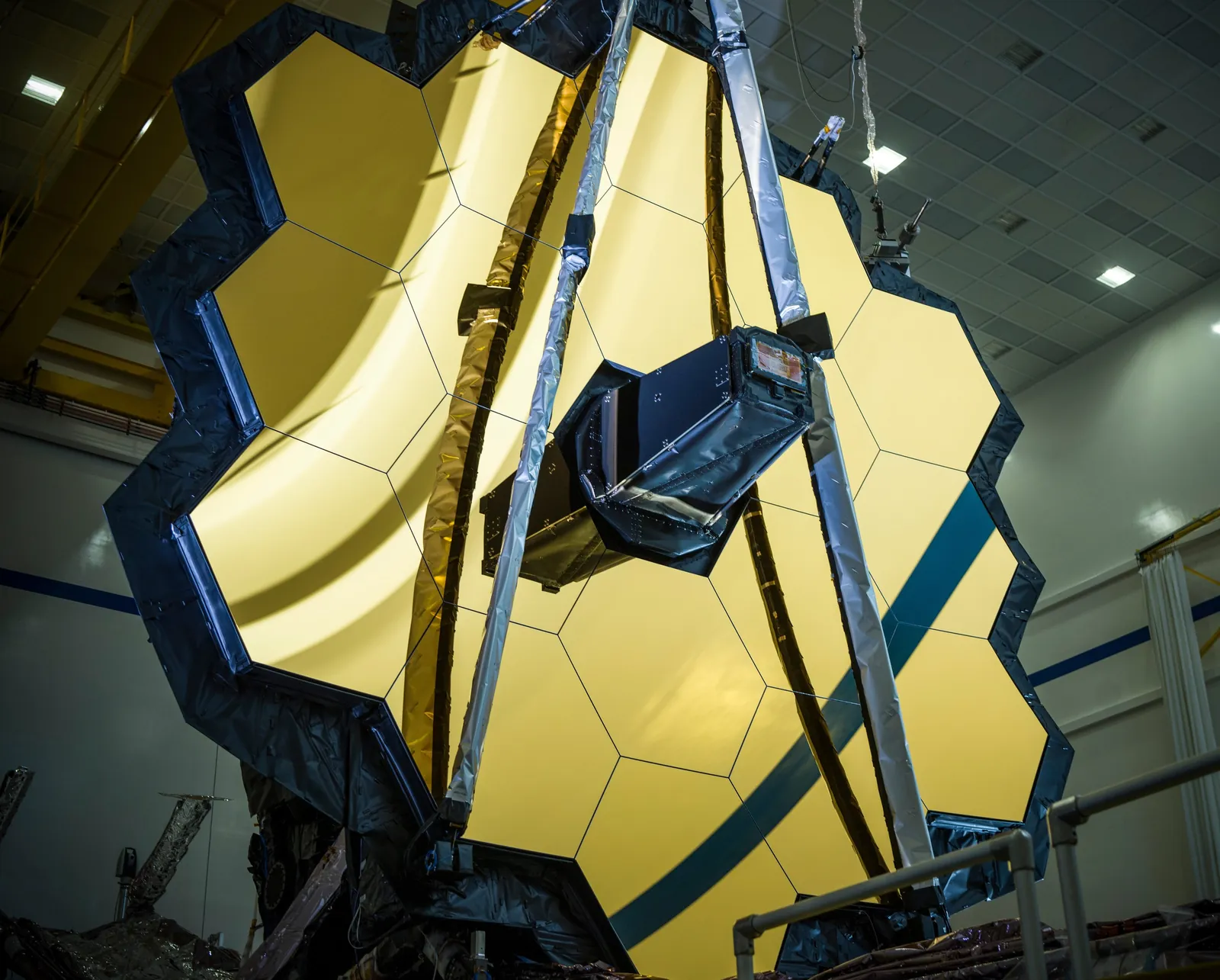 The segmented primary mirror of the James Webb Space Telescope with its secondary mirror support in a cleanroom before launch.